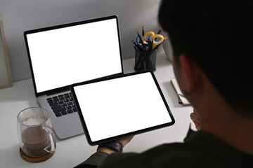 View over shoulder businessman sitting at office desk and using digital tablet.