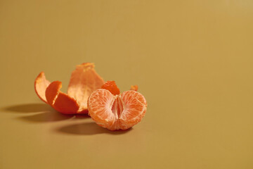 Half a peeled tangerine and peel on a colored background