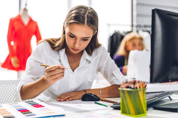 Portrait of young beautiful pretty owner business woman fashion designer stylish sitting and working.Attractive young designer girl use desktop conputer and colorful fabrics at fashion studio