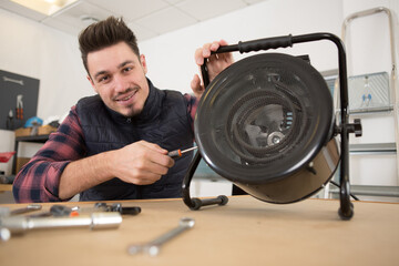 male technician repairing fan at workshop