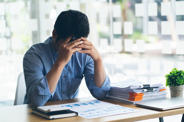 Stressed businessman Feeling sick and tired while sitting at his working place in office, deadline concept