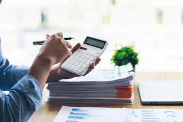 A financial businessman, a young man analyzes financial data using a computer and calculator to...