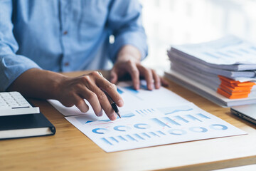 A financial businessman, a young man analyzes financial data using a computer and calculator to compute and summarize the data in a graph to propose to the president.