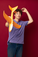 A young man with toy airplane entertainment red background unaltered