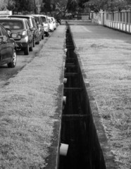 a line of cars parking next to a drain in black a d white