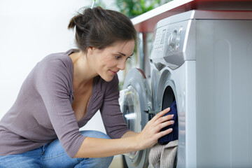 woman crouched down to use washing machine