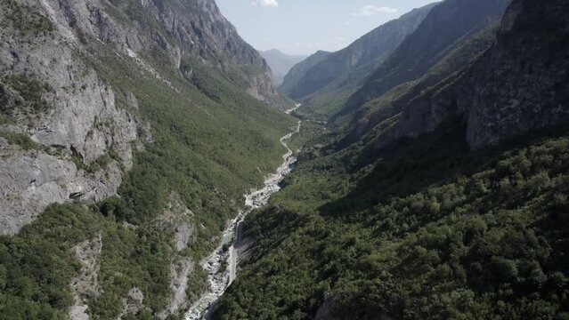Drone video of frontal plane ascending between the hills of the valbone valley and over the Azem Hajdariy road and the river. The beauty of the landscape can be appreciated from a bird's eye view.