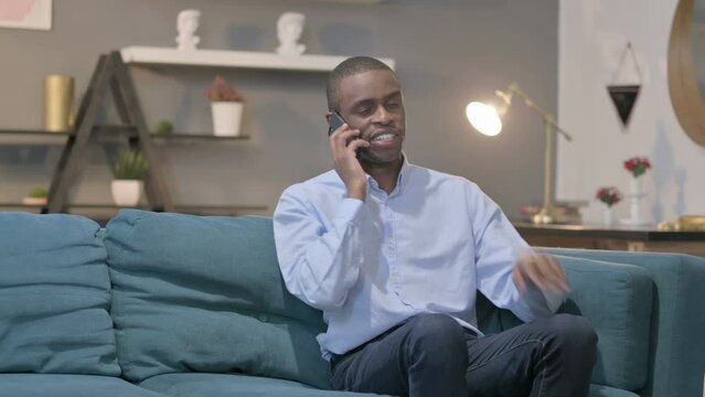 African Man Talking on Smartphone on Sofa 