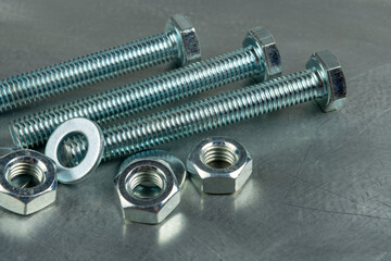 Fasteners for assembling threaded connections. Nuts and bolts. Close-up on the background of a metal blank. Copy space