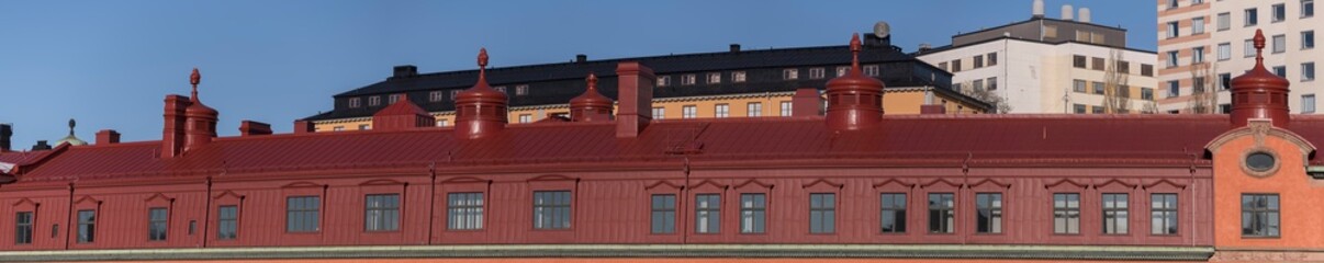 Obraz premium Old red tin roof on an old yellow stone house a sunny winter day in Stockholm, Sweden 2022-02-20
