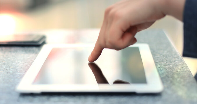 Woman hand touching screen on modern digital tablet pc. Close-up image with shallow depth of field focus on finger