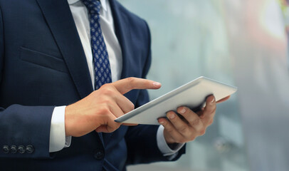 Midsection of businessman using digital tablet in office.