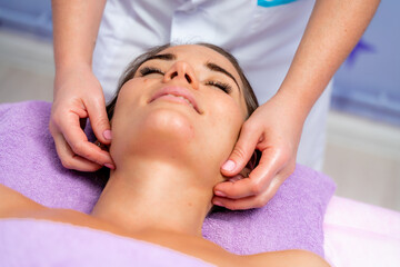 Fototapeta na wymiar Relaxing massage. European woman getting facial massage in spa salon, side view