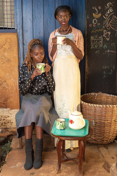 Two young African women sharing a pot of tea