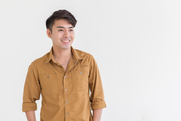 Portrait isolated cutout studio shot Asian young happy trendy male businessman model in casual brown long sleeve shirt with earring standing smiling holding hand in pants pocket on white background