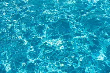 Fototapeta premium Water background, ripple waves. Blue swiming pool pattern. Sea surface. Water in swimming pool with sun reflection. Banner with copy space.