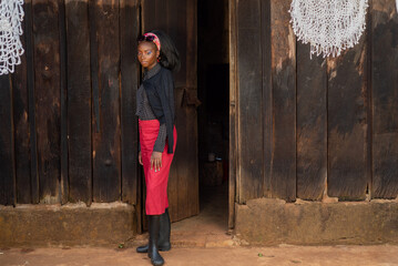 Portrait of young African woman  in front of a wooden house 