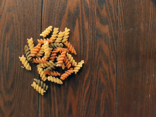 orange, yellow, and green fusilli on wooden background