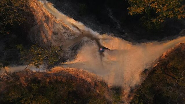 Young blond woman walks slowly down the narrow paths with huge precipices of Pai Canyon right next to her during Golden hour. Top down drone panning shot