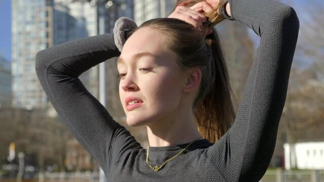 Beautiful young woman tying hair before morning run