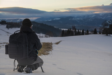 Fototapeta na wymiar Photographer taking pictures of mountain landscape in winter