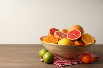 Different citrus fruits on wooden table, space for text