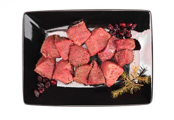 Raw game meat, beef on black plate, isolated. Diced red meat, top view. High quality roe, deer meat.