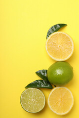 Lemon and lime halves with leaves on yellow background