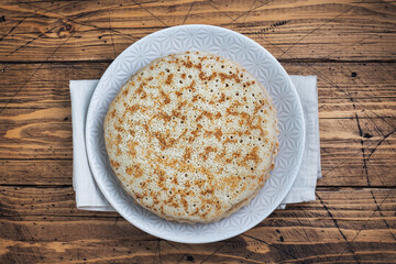 Thin pancakes on a plate, top view, wooden background. The concept of a delicious breakfast or Maslenitsa. copy space