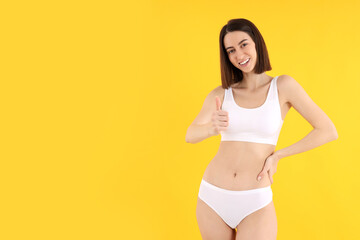 Obraz premium Concept of weight loss with young slim woman on yellow background