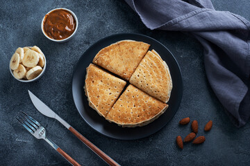 Pancakes with chocolate banana filling. Delicious breakfast of pancakes envelopes on a plate, dark concrete background.