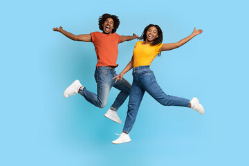 Fototapeta na wymiar Joyful african american man and woman jumping up on blue