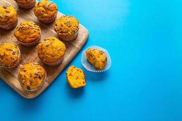 Pumpkin muffins with spices and seeds on blue background. Copy space. Autumn, halloween, thanksgiving baking concept.