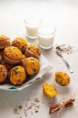 Pumpkin muffins with spices and seeds and milk on light background. Copy space. Autumn, halloween, thanksgiving baking concept.