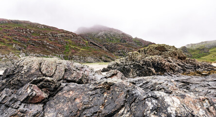 hills with purple heather covered in thick clouds with rocks in the foreground Isle of Colonsay, Inner Hebrides, Scotland