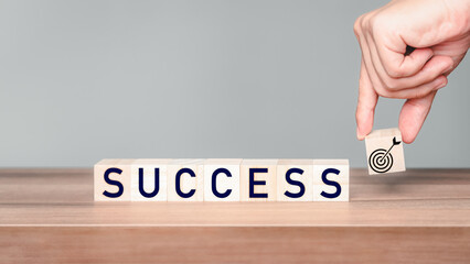 Hand put a goal icon on wooden cubes block with the inscription "success". Business growth in concept.
