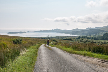 lonely cyclist cycling on up a road on the Isle of Jura on a beautiful simmer day