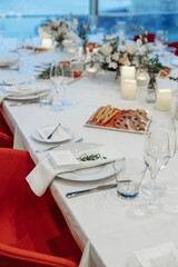 Festive table setting for a wedding or banquet with a panoramic view of the city, red chairs.