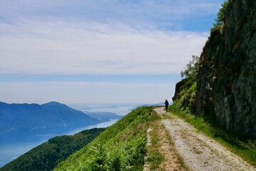 Man hiking on old military road in the mountains above Lake Maggiore offering splendid views. Lombardy, Italy.