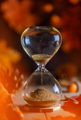 hourglass. red, orange leaves. concept of time, the onset of autumn season