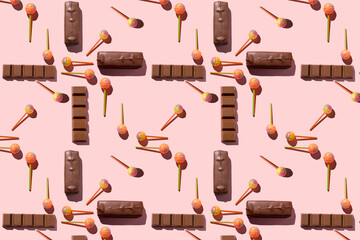 Colorful Set of Lollipops and chocolate. pattern made with caramel on a stick and chocolate on bright pink background. creative pattern.