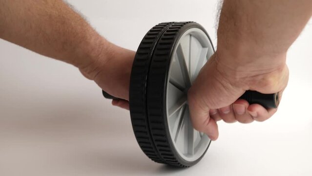 A man holds a gymnastic wheel with both hands to perform sports exercises.