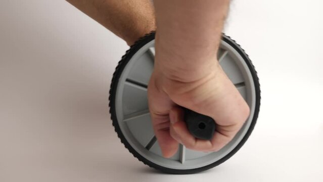A man holds a gymnastic wheel with both hands to perform sports exercises.