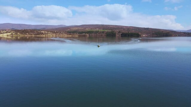 Moving fishing motorboat at the lake. Aerial view of drone forward. Summer tourism