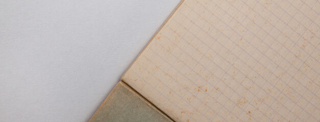 Fragment of a checkered notebook with yellowed old paper lying on a white sheet, close-up.