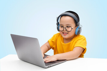 Little boy wearing headphones using laptop, happy learning,  listening audio course, e-learning education concept