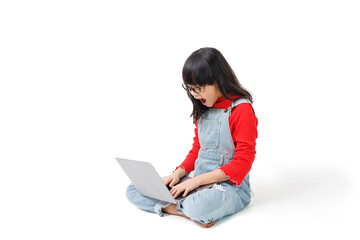 A young girl sat on the floor, working on a computer, with a surprised expression on her face.