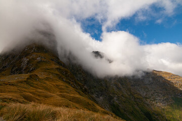 Mount Balloon covered by soft fog touching sunlight from cloudy sky, Milford track, New Zealand