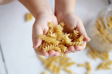 fusilli pasta in the hands of a girl