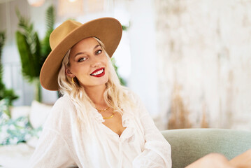Portrait of fashionable young woman wearing hat and red lipstick while looking at camera and smiling